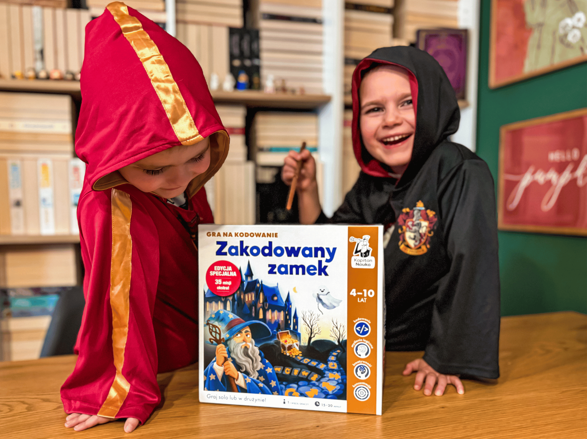 Uśmiechnięte dzieci w pelerynach czarodziejów z grą Zakodowany zamek w edycji specjalnej